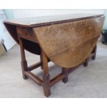 An 18th/19thC style rustic oak drop-leaf dining table with an end drawer, the oval top raised on