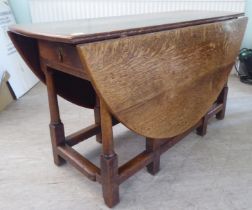 An 18th/19thC style rustic oak drop-leaf dining table with an end drawer, the oval top raised on