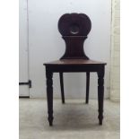 A William IV mahogany hall chair with a twin C-scroll design back, the solid seat raised on ring