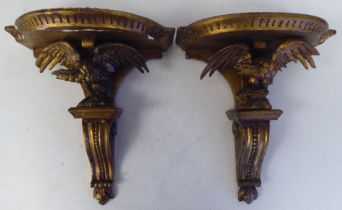 A pair of late 19thC carved wooden and gilt gesso moulded wall brackets, each featuring a semi-