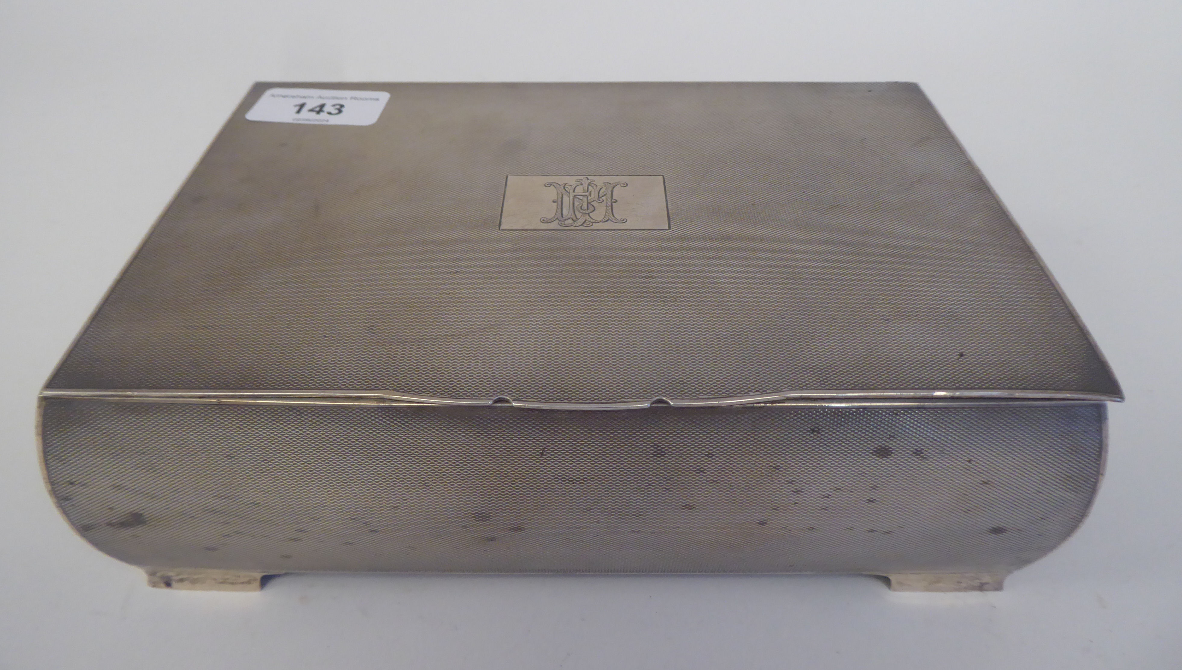 A silver cigarette box with allover engine turned decoration, the hinged lid enclosing a maple lined