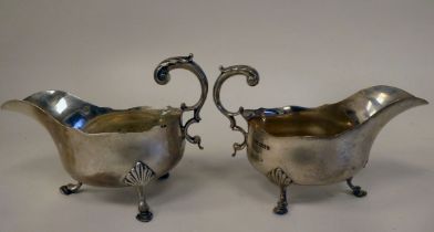 A pair of silver sauce boats with cut, wavy rims and double C-scrolled handles, elevated on shell