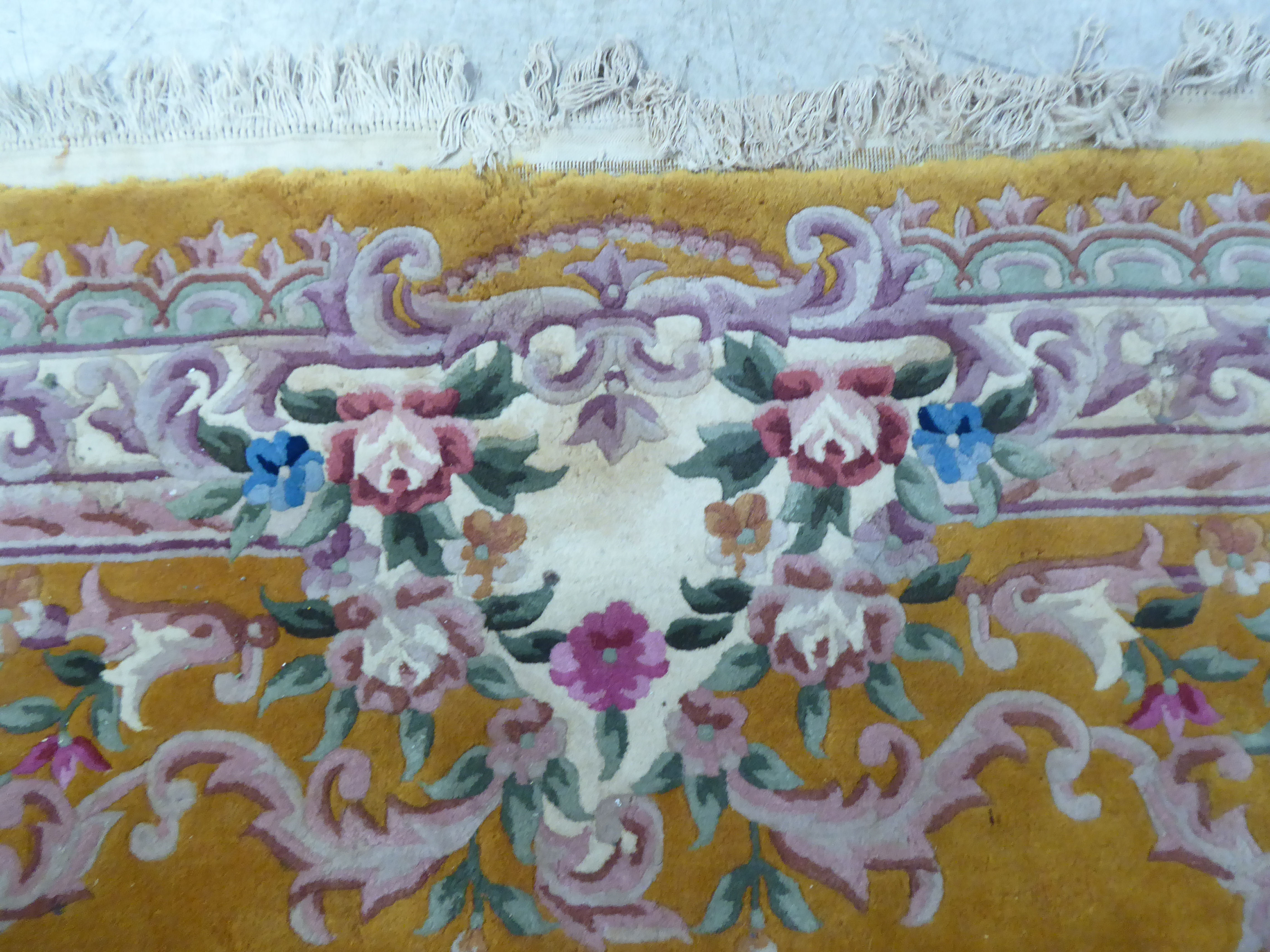 A traditional 20thC Chinese washed woollen carpet, decorated with flora, on a mustard coloured - Image 5 of 6
