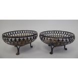 A pair of silver sweet baskets with decoratively pierced, shallow sides, elevated on three paw feet