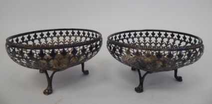 A pair of silver sweet baskets with decoratively pierced, shallow sides, elevated on three paw feet