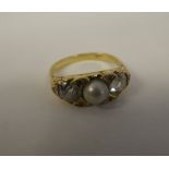 A gold coloured metal ring with a scrolled shank, rubover set with two diamonds and a single