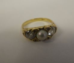 A gold coloured metal ring with a scrolled shank, rubover set with two diamonds and a single