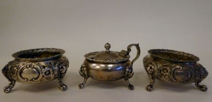 A pair of early Victorian silver shallow, bulbous salt cellars with embossed floral decoration,