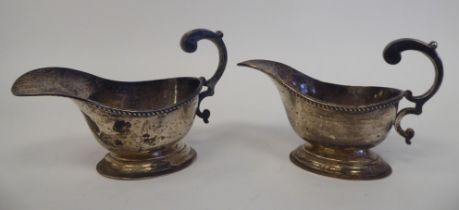 A pair of silver oval sauce boats, each with a gadrooned rim and hollow, double C-scrolled handle,
