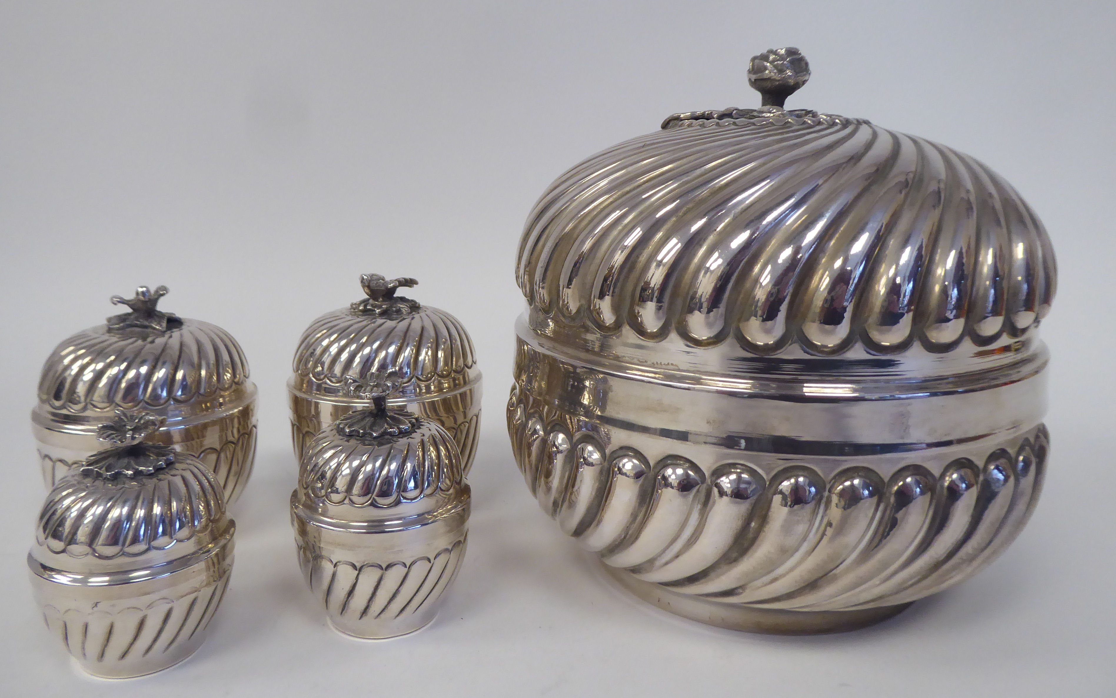 A matched set of silver coloured metal tableware with embossed, swirling, demi-reeded ornament