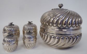 A matched set of silver coloured metal tableware with embossed, swirling, demi-reeded ornament