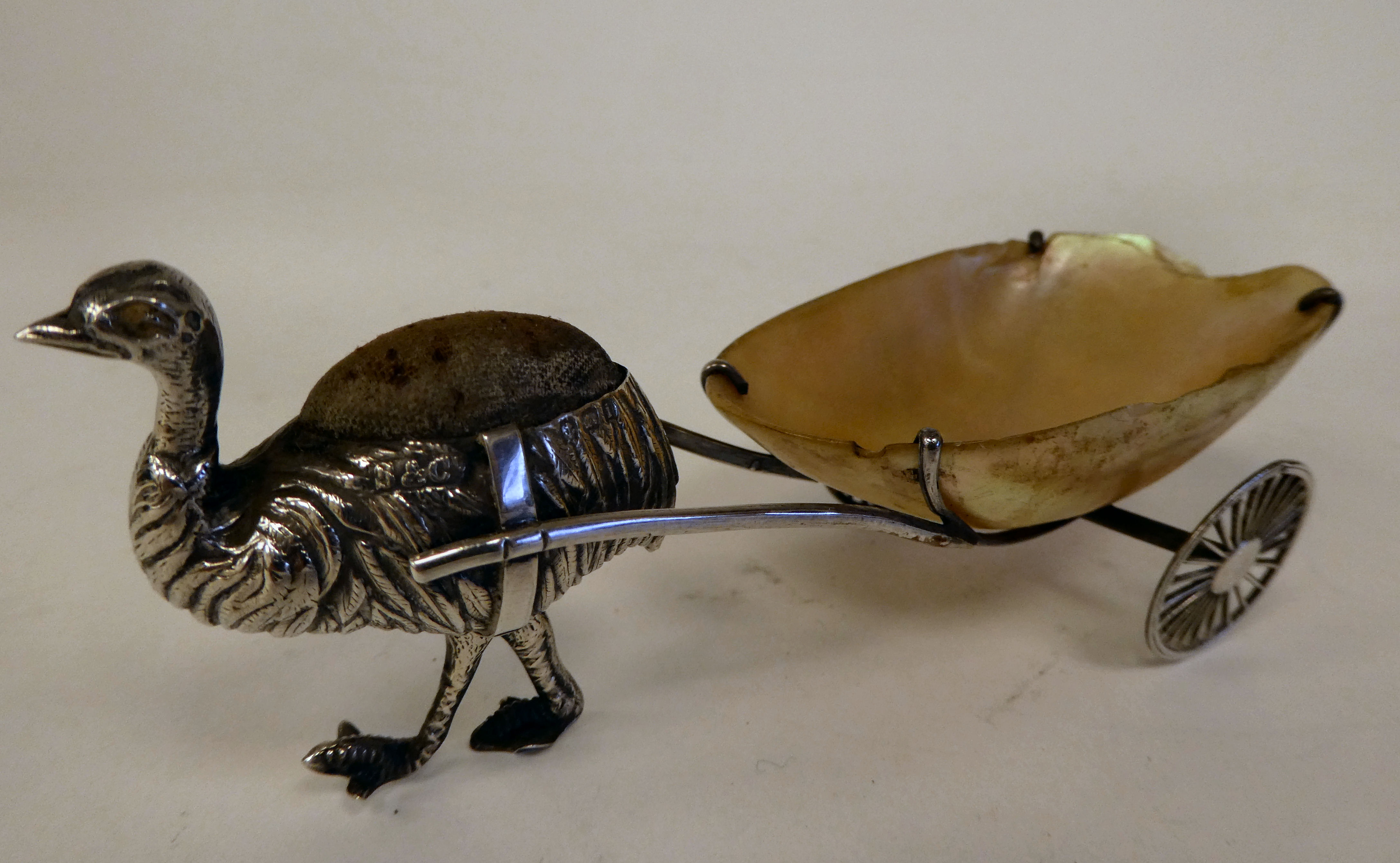 An Edwardian novelty silver pin cushion, fashioned as an ostrich pulling a two wheeled seashell  S &