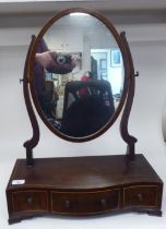 An Edwardian satinwood string inlaid mahogany toilet mirror, the oval plate pivoting on shaped