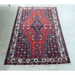 A Persian rug, decorated with stylised designs, on a red ground  52" x 75"