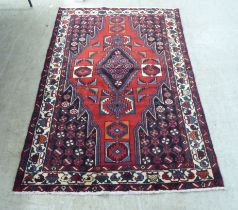 A Persian rug, decorated with stylised designs, on a red ground  52" x 75"