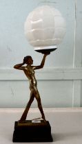 A 1930s Art Deco patinated and gilded table lamp. fashioned as a woman holding a white glass
