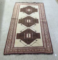 A Persian Gabbeh tribal rug, decorated with three repeating central motifs, bordered by stylised