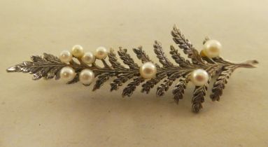 A white metal brooch, fashioned as a fern, set with seed pearls