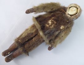 An early 20thC Inuit doll with a carved bone face and seal skin clothes  10.5"h