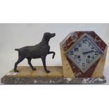 An Art Deco multi-coloured marble cased mantel clock, surmounted by a spelter standing hound; the