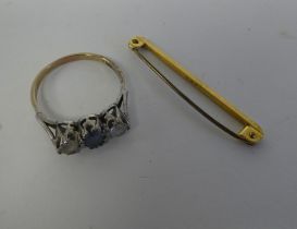 A 9ct gold claw set, three stone ring; and a 9ct gold bar brooch