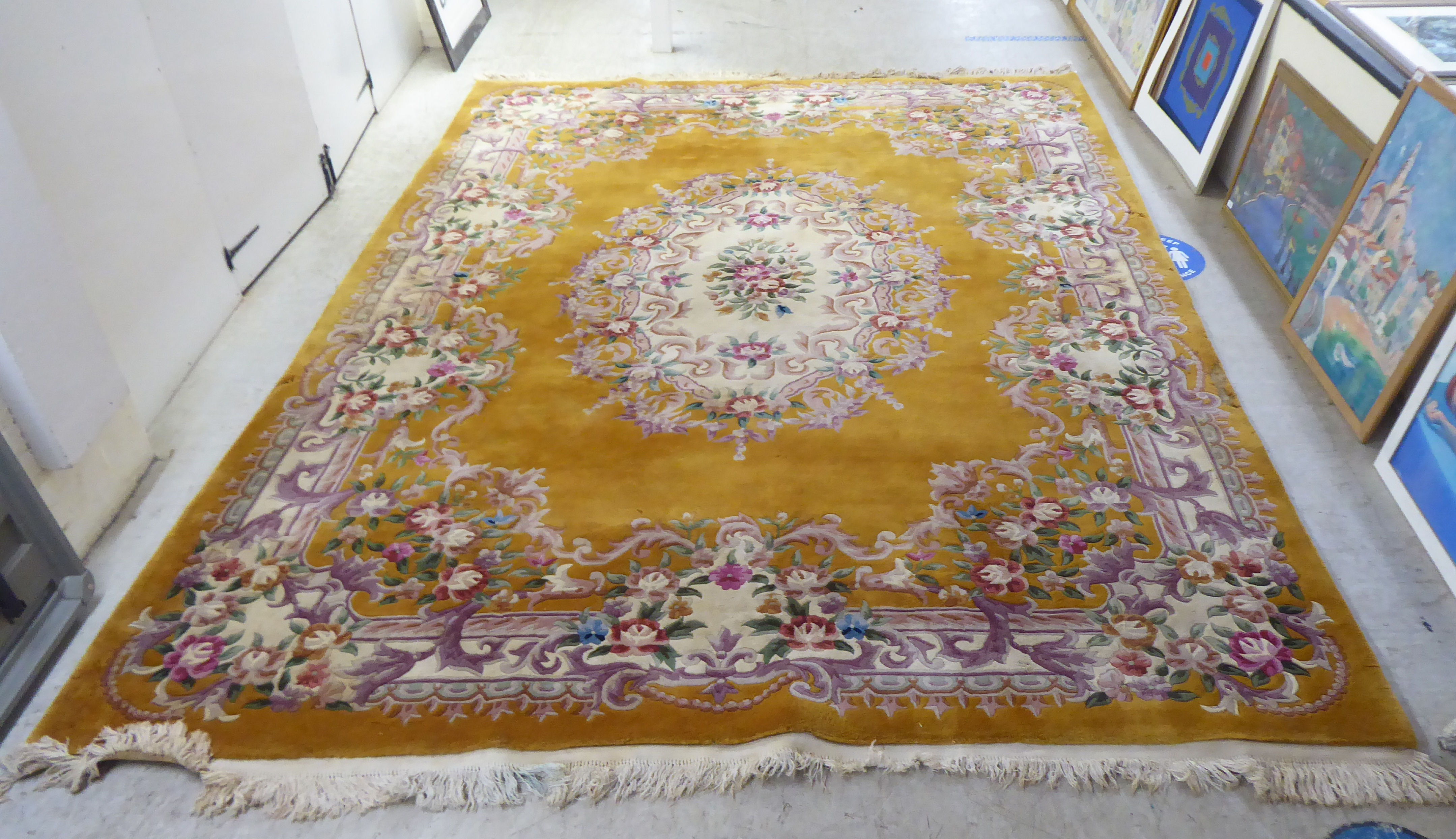 A traditional 20thC Chinese washed woollen carpet, decorated with flora, on a mustard coloured