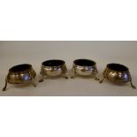 A pair of George III silver shallow, bulbous salt cellars with blue glass liners, on hoof feet