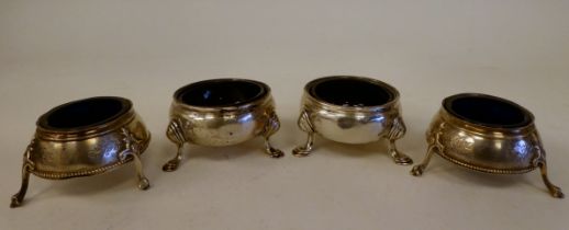 A pair of George III silver shallow, bulbous salt cellars with blue glass liners, on hoof feet