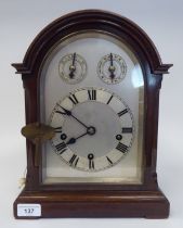 A late 19th/early 20thC mahogany round arched cased mantel clock with a full-height window, on a