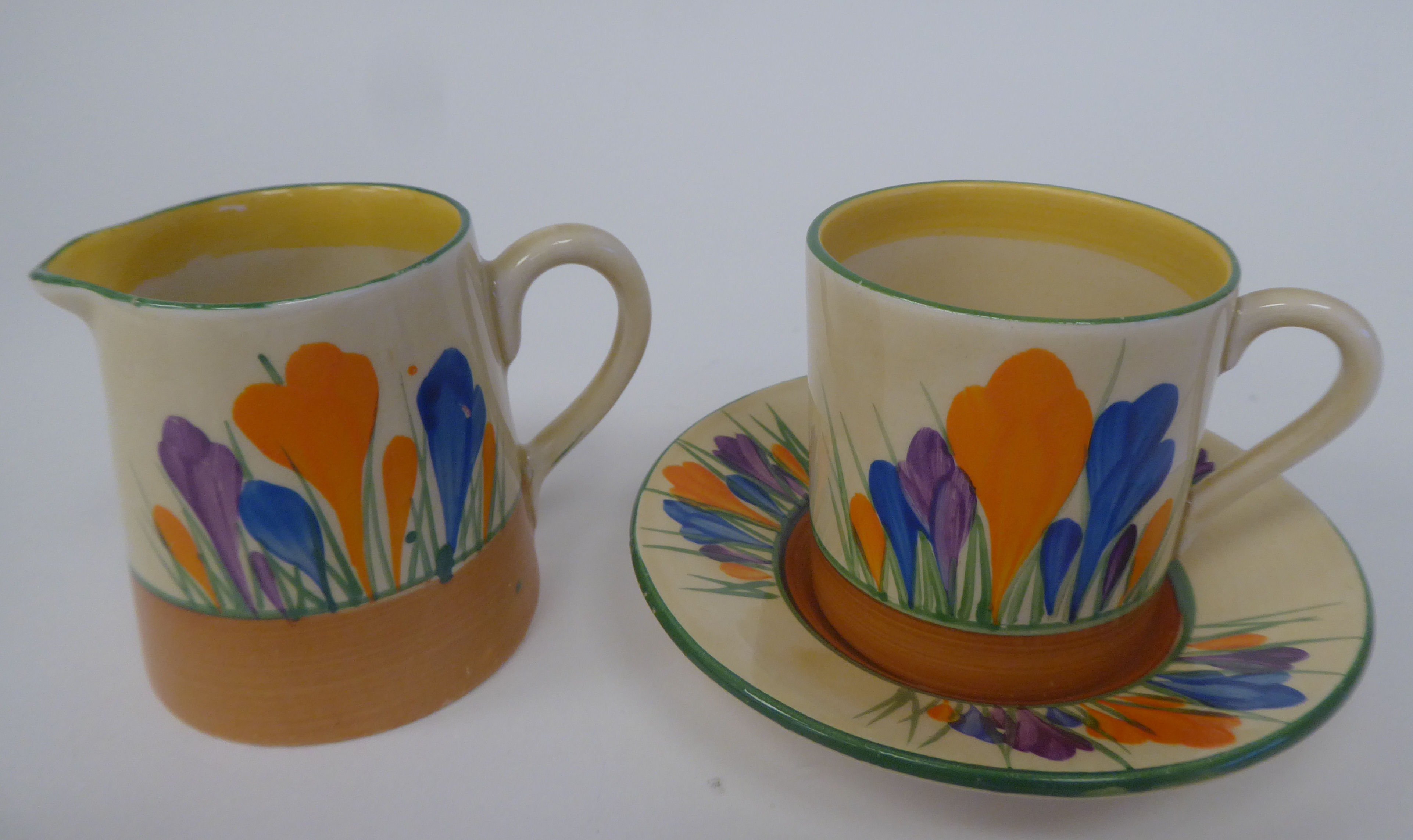 A Clarice Cliff Bizarre, Newport Pottery, Crocus pattern cream jug; and a demi-tasse coffee can