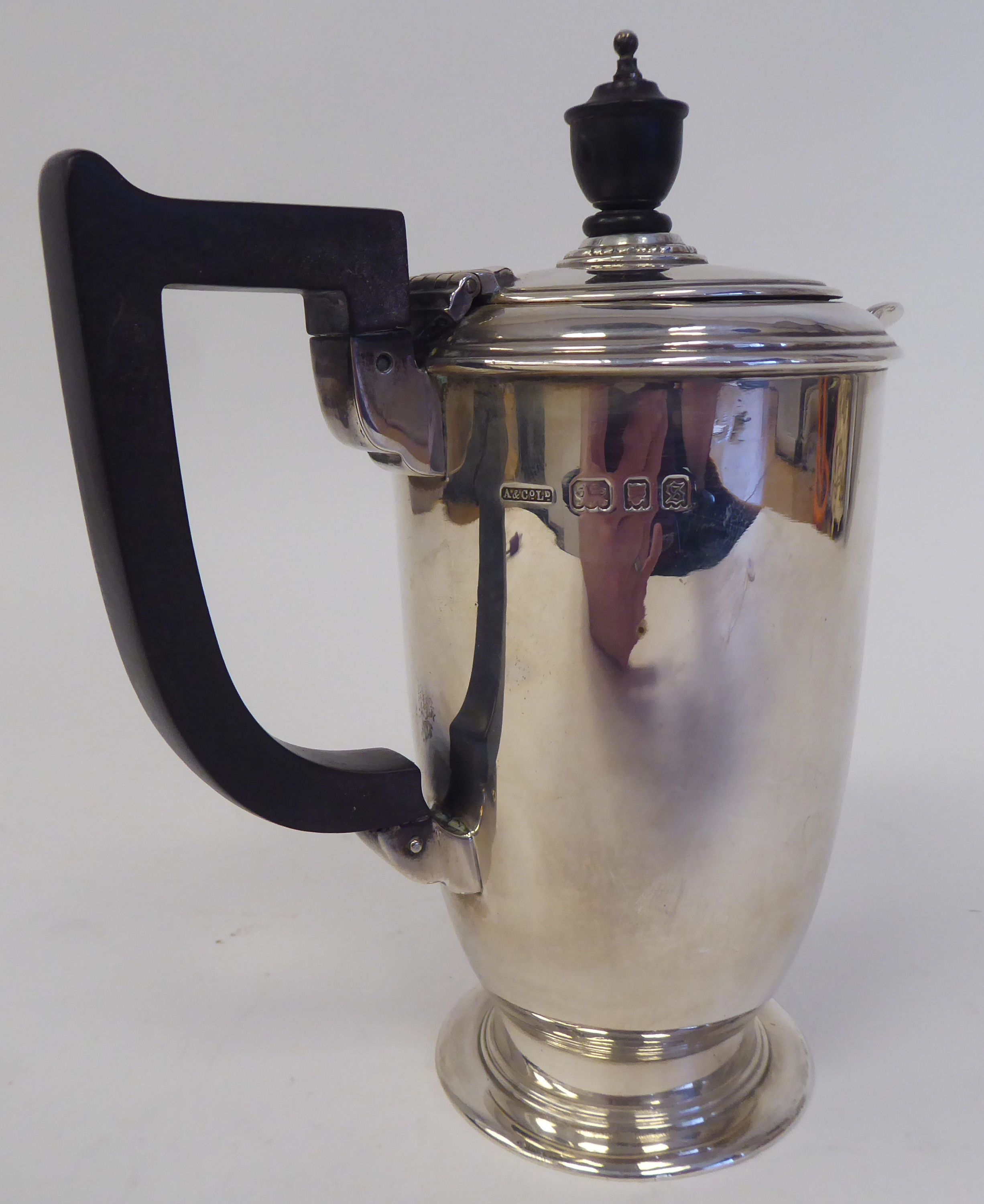 A silver hot water pot of baluster form with a hinged lid, ebonised handle and knop, on a splayed - Image 2 of 3