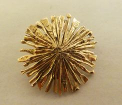 A yellow metal sunburst design brooch