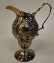 A late Victorian silver pedestal cream jug of pear form with a double C-scrolled handle, scaled,