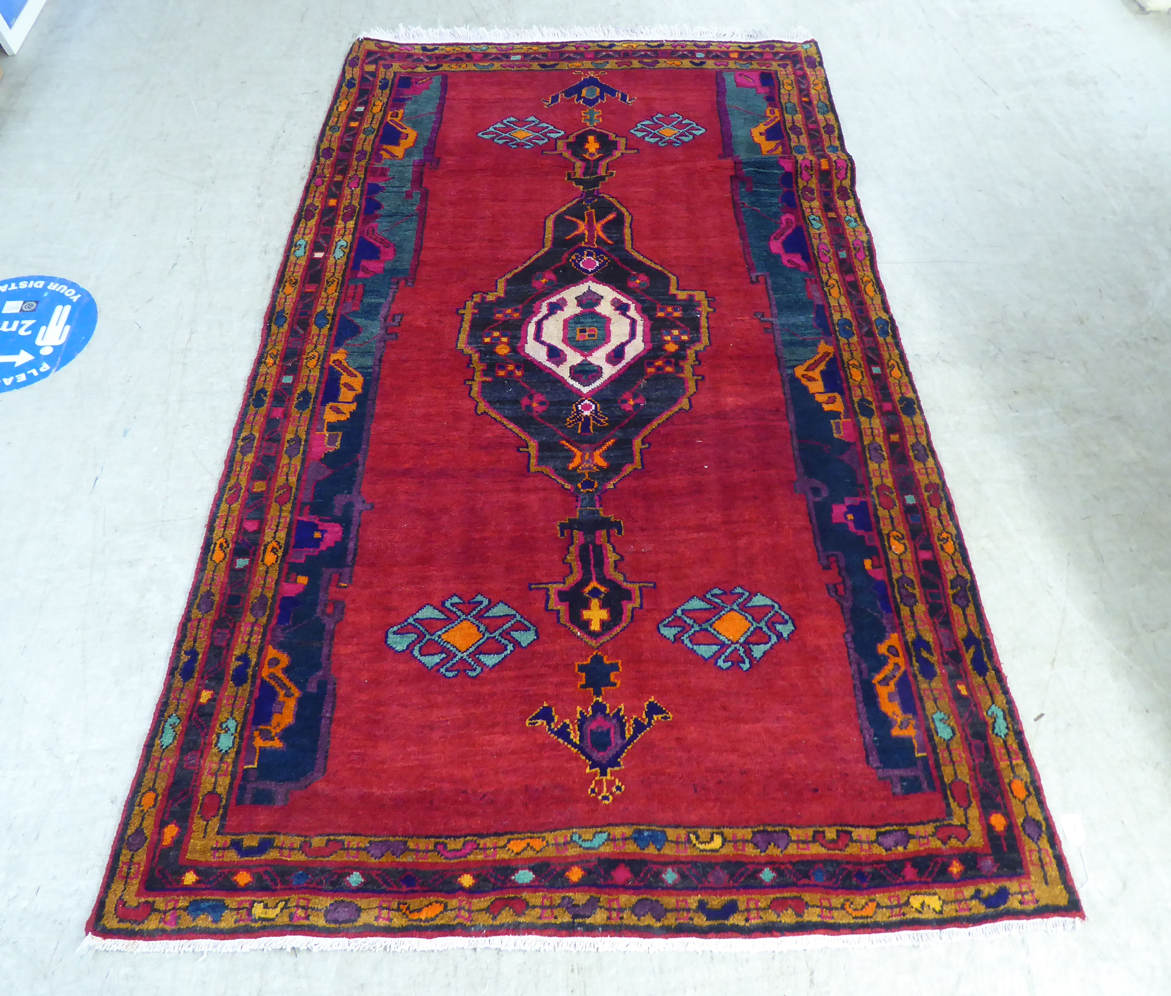 A Turkish rug with stylised designs, on a mainly red ground  52" x 88"