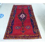 A Turkish rug with stylised designs, on a mainly red ground  52" x 88"