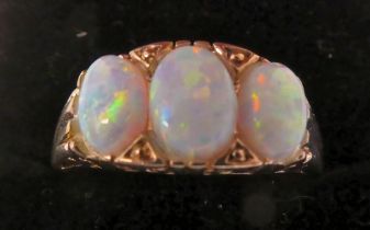A yellow metal three stone opal ring