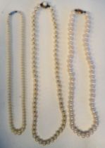 Three single strand pearl necklaces, each on a yellow metal clasp