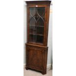 A modern yewwood corner cabinet with a glazed, panelled door, raised on bracket feet  75"h  26"w