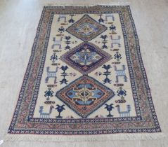 A Turkish rug, decorated with three diamond shaped motifs, bordered by stylised designs, on a
