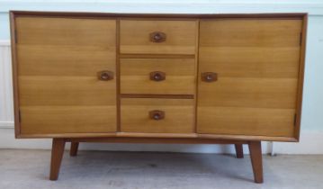 A 1970s two-tone teak inverted breakfront sideboard with a bank of three central drawers, flanked by