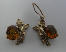 A pair of 9ct gold earrings, fashioned as cherubs, holding amber coloured stones