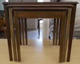 A nesting set of three modern crossbanded mahogany occasional tables, raised on square, tapered legs