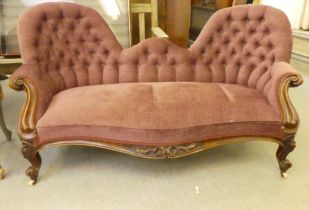 A mid Victorian scroll carved mahogany showwood framed, double spoonback settee, part button