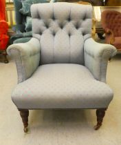 A late 19thC Howard style armchair, button upholstered in blue fabric, raised on turned walnut