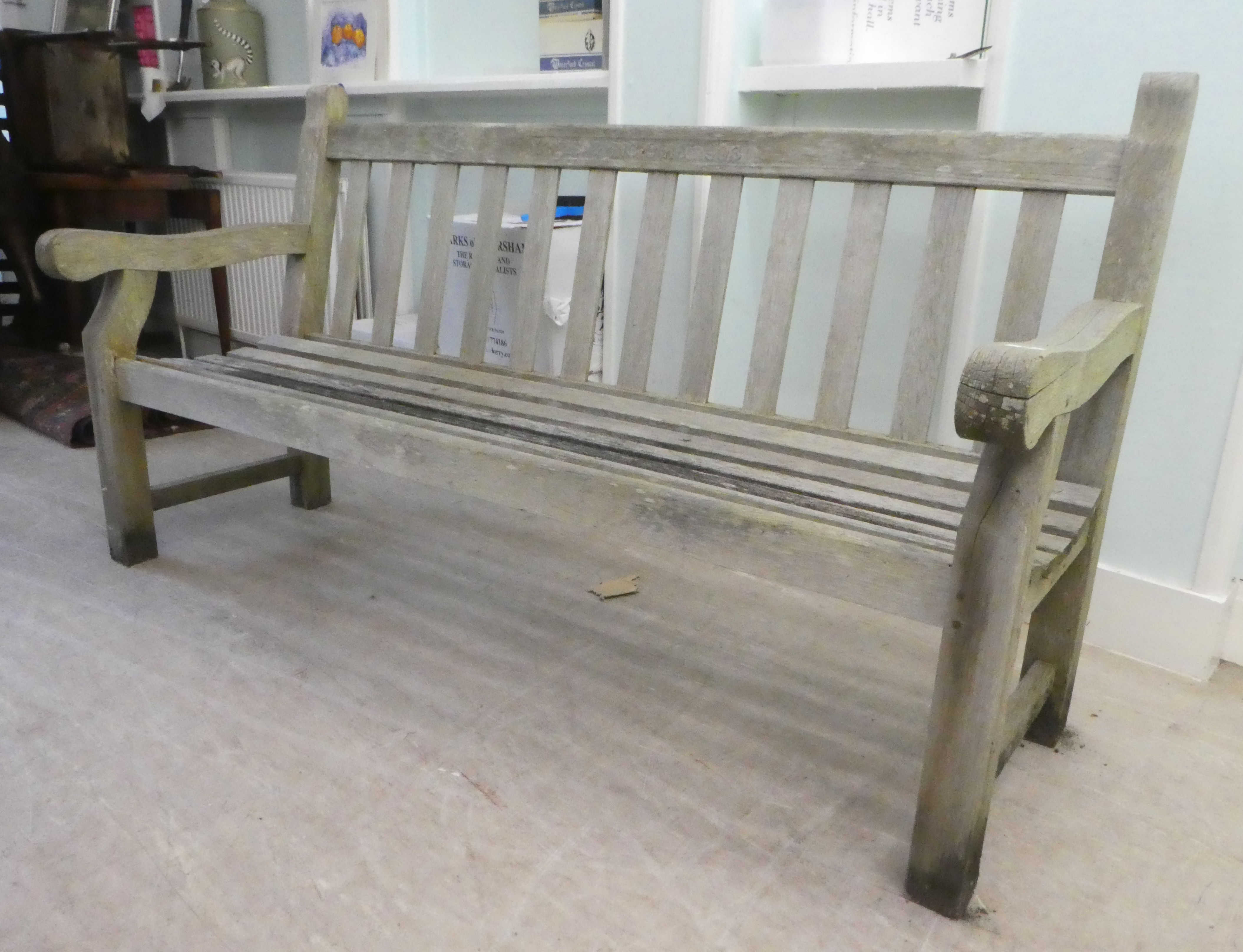 A slatted weathered teak garden bench, raised on square legs  70"w