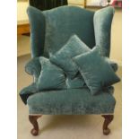 A 20thC Georgian style wingback chair with scrolled arms, upholstered in crushed turquoise