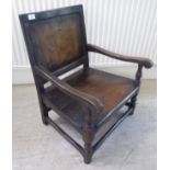 An antique finished, dark stained oak floral marquetry, panelled back, low, open arm chair with a