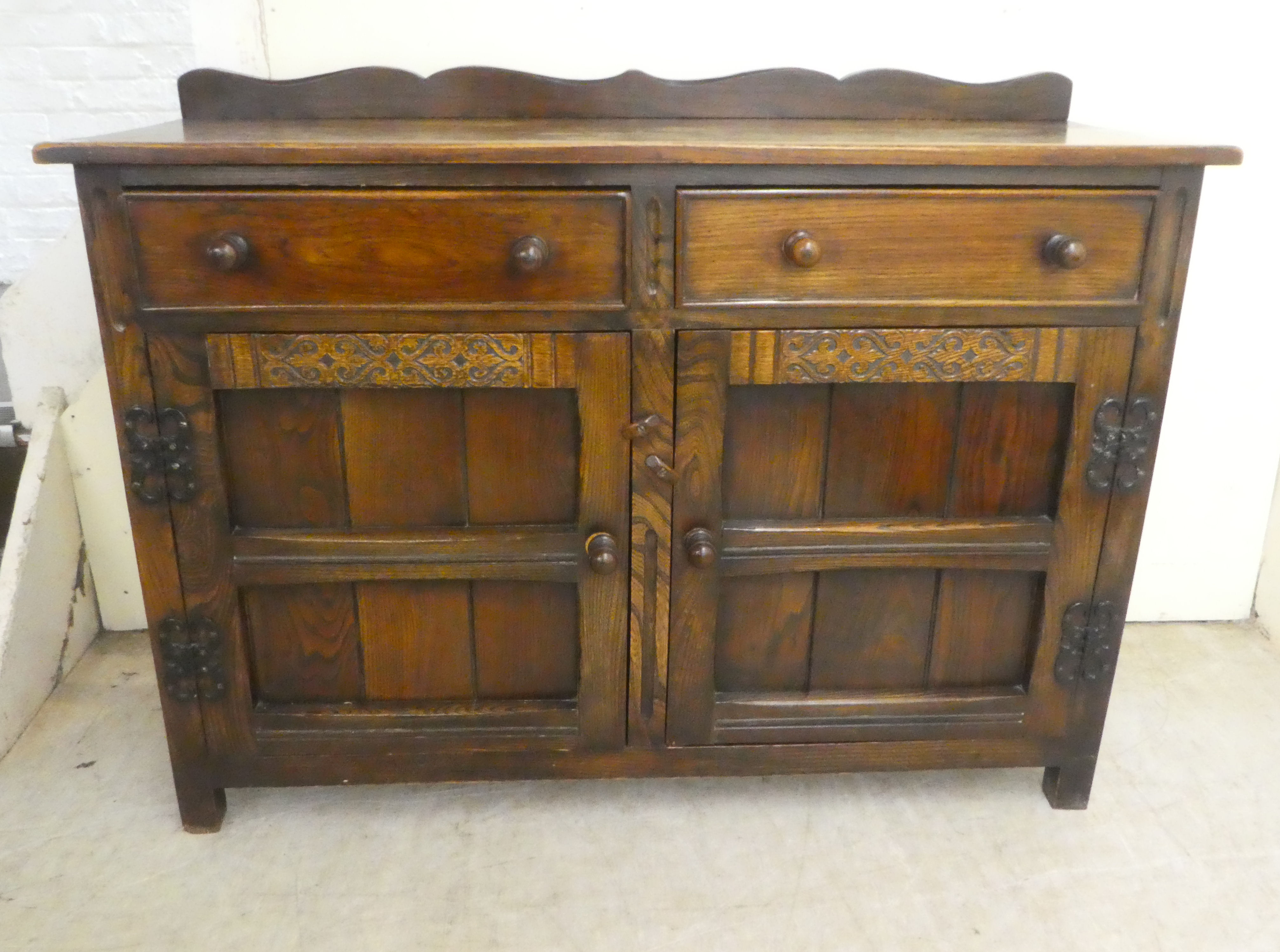 A 20thC Old English style oak dresser with two frieze drawers, over two panelled doors, raised on