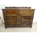 A 20thC Old English style oak dresser with two frieze drawers, over two panelled doors, raised on