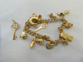 A 9ct gold ring link charm bracelet with pendants including a mobile phone and a racing car